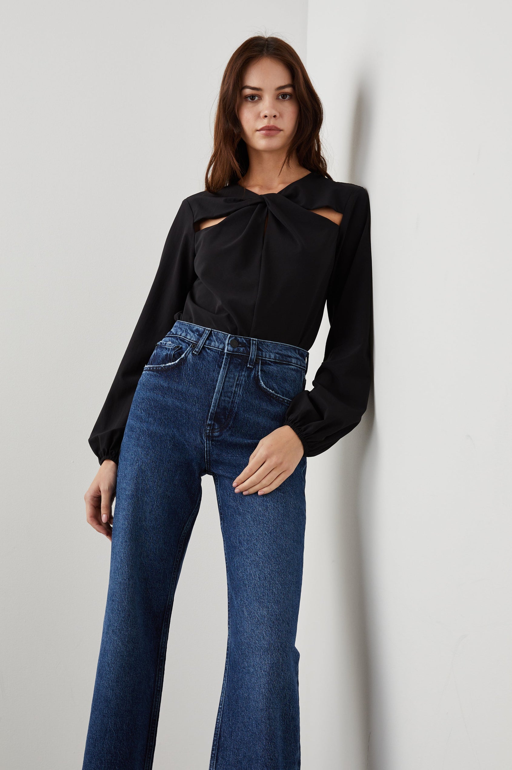 Eli Long-Sleeve Top with Twisted Fabric at the Neckline and a Cutout to the Left and Right of the Twist, a Vertical Seam Down the Front and a Keyhole at the Back in Black Colorway - Front Full Body View Featured on Model 