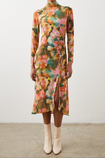 Mona Long Sleeve Midi Dress with a Mock Neck, a Side Slit and Adjustable Ruching along the Left Side with a Drawstring in Terra Floral Colorway, Flowers in Pinks, Browns, Yellows and Blues on Olive - Front Full Body View Featured on Model 