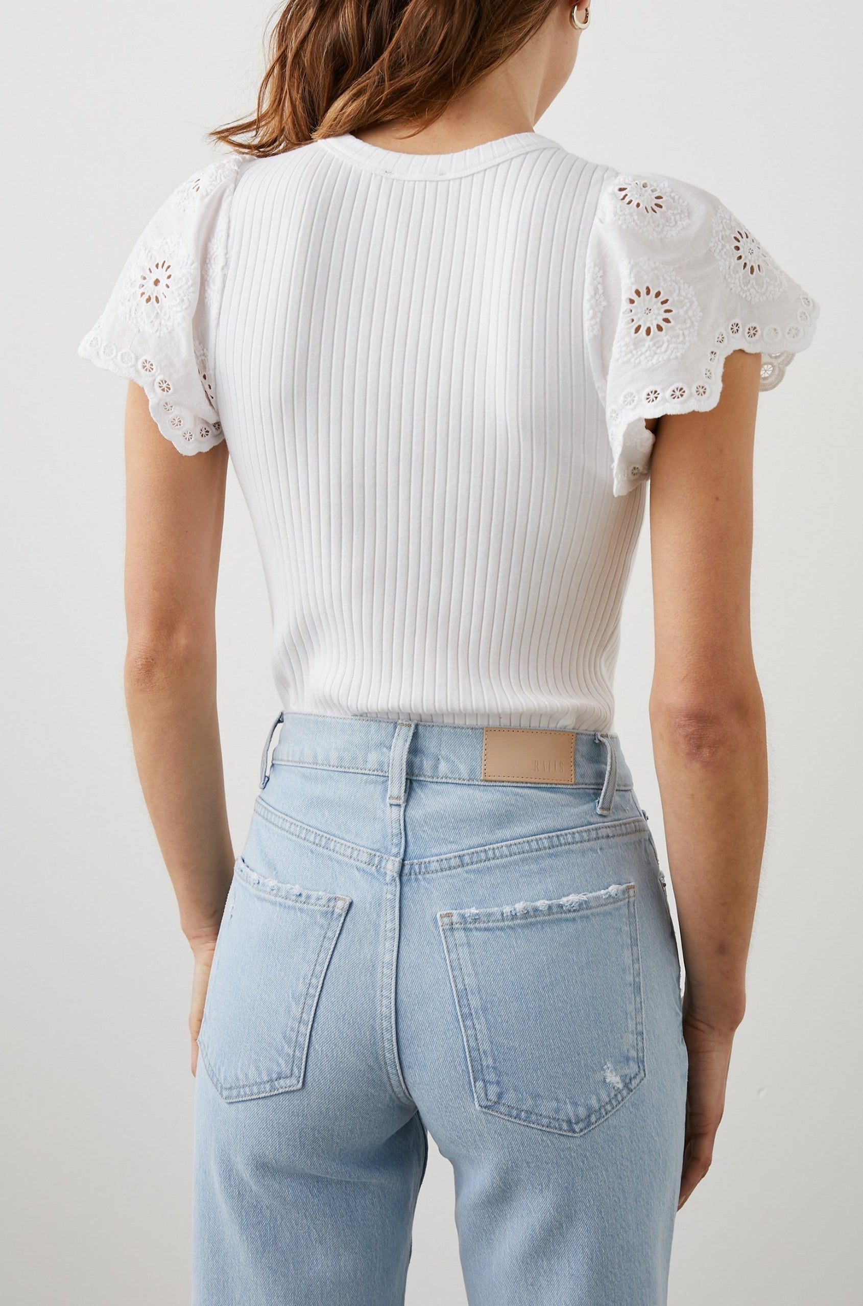 Reza Ribbed Short Sleeve Top with Flutter Sleeves, a Crew Neck and Floral Eyelets on the Sleeves in White Colorway - Back Tucked View Featured on Model 