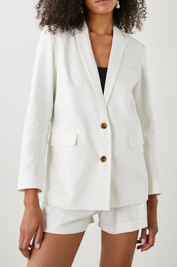 Stanton Blazer with Two Button Closure, Two Front Flap Pockets, a Chest Patch Pocket and Four-Button Cuffs in Creme Colorway - Front View Featured on Model